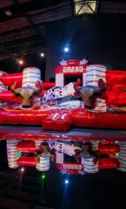 Participante disfrutando un toro mecánico con colchón inflable de seguridad durante un evento.